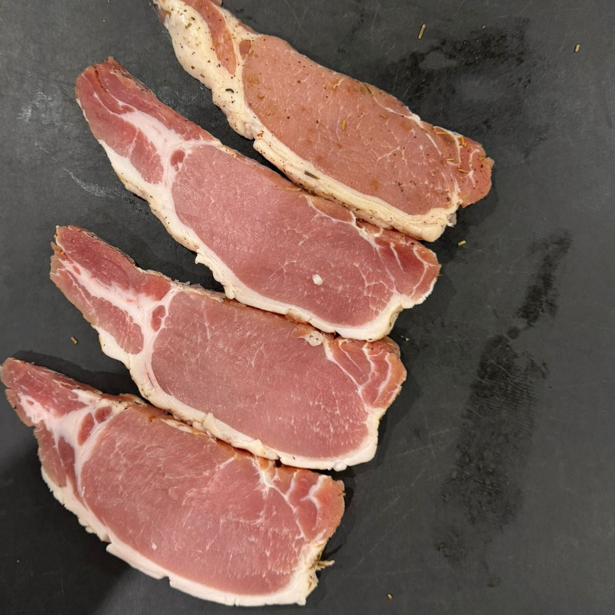 Sliced cured bacon on a black surface
