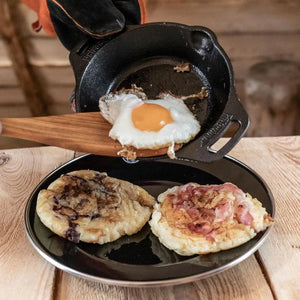 Petromax 30cm Cast Iron Fire Skillet with Two Handles frying an egg, served with pancakes, showcasing its versatility for indoor and outdoor use.