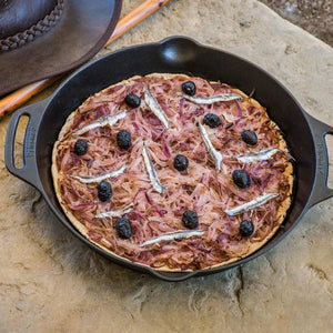 Petromax 30cm Cast Iron Fire Skillet with Two Handles used to bake a savory tart with anchovies and olives, great for rustic outdoor meals.