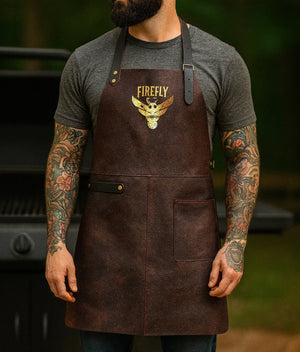 Leather BBQ Apron - Stalwart Crafts | Adjustable, Vintage-Style apron worn by man at grill. Features Firefly logo and two-tone leather design.