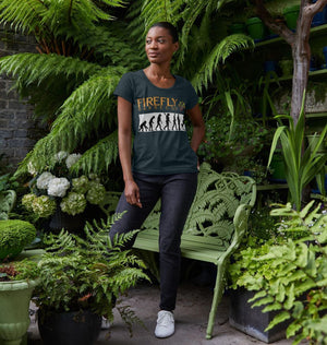 Woman in garden wearing dark green Women's BBQ Evolution V Neck T-Shirt featuring Firefly Barbecue logo and grilling evolution design.