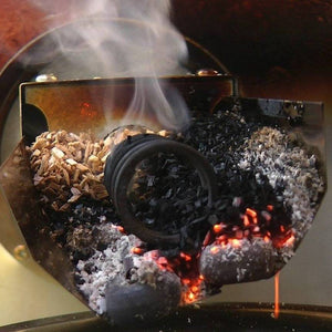 Burning wood chips inside Borniak BBQ Smoker 150L Stainless Steel for authentic smoke flavor in meat preparation.