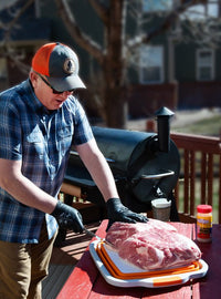 Man preparing meat on outdoor grill with BBQ prep tub