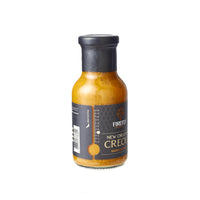 Side view of Firefly BBQ New Orleans Creole Sauce bottle with textured black label, highlighting premium packaging for retail shelves.