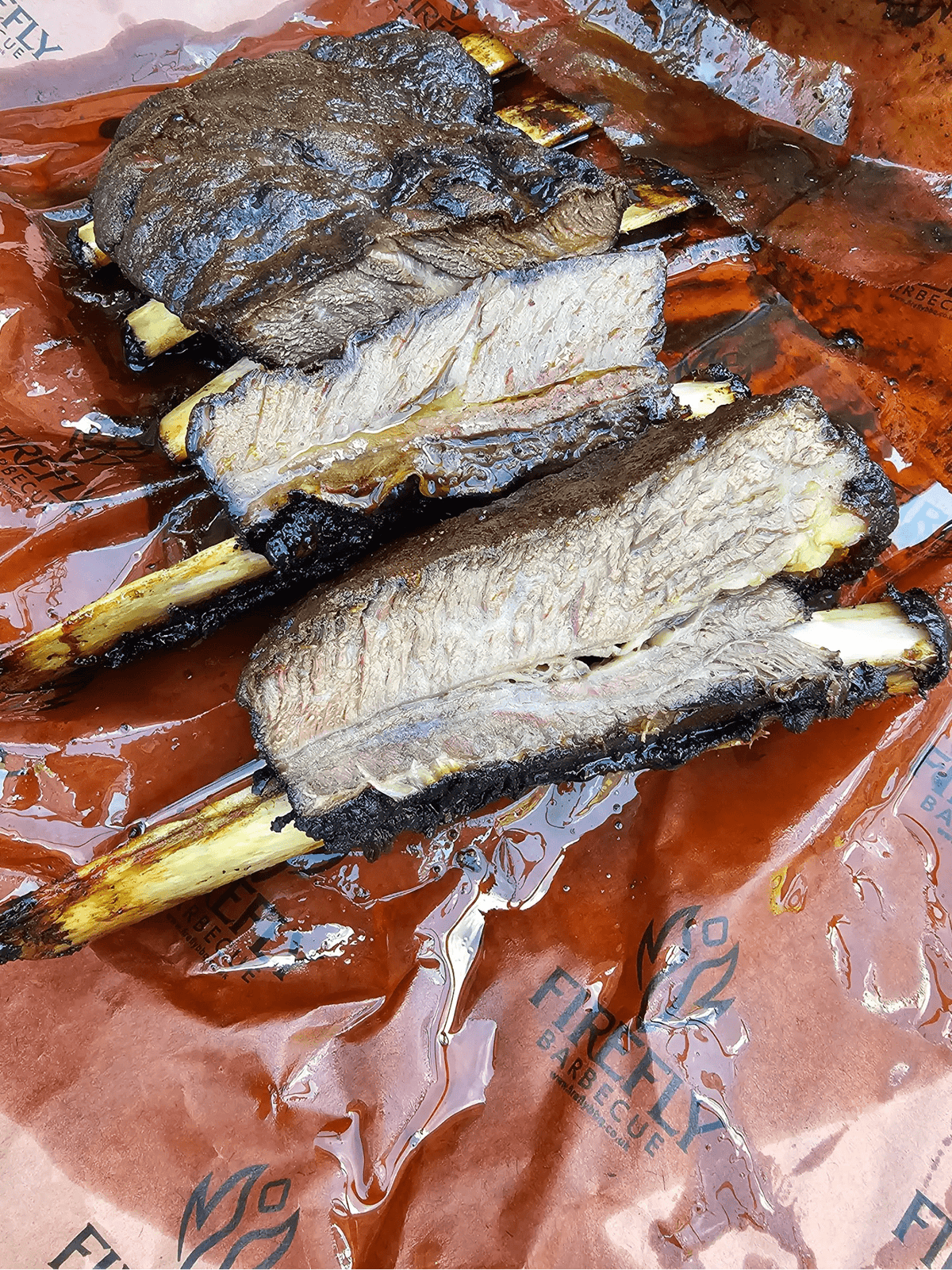 Beef ribs resting on OREN Pink Butchers Paper Roll - BBQ Meat Smoking | FDA Approved, demonstrating grease resistance and meat smoking efficiency.