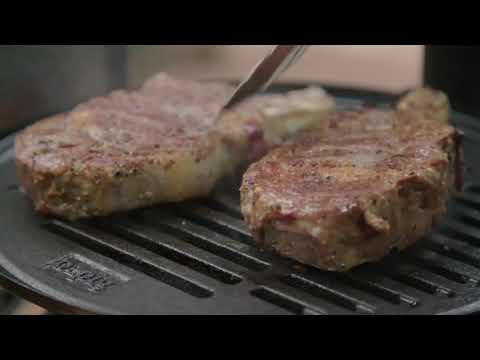 Ozpig Chargrill and Drip Tray - FireFly Barbecue in use with sizzling steaks on cast iron grill, delivering authentic wood fired flavor outdoors.