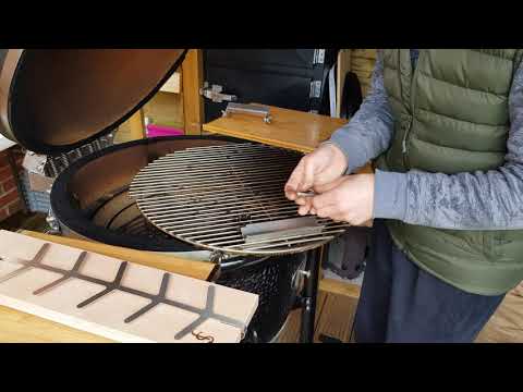 User installing stainless steel bracket for Monolith Fish Plank - Beech on ceramic grill, preparing for vertical fish grilling.