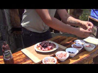 Ozpig Oven Pizza Stone - Perfect Crusts | Easy Cooking. Person preparing toppings for pizza next to Ozpig accessories, showcasing outdoor cooking setup.