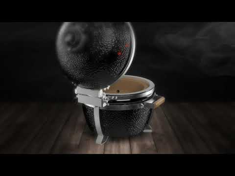 Stylized product image of MONOLITH Icon Portable Kamado Grill on wooden floor with smoke effect, emphasizing premium outdoor cooking design.