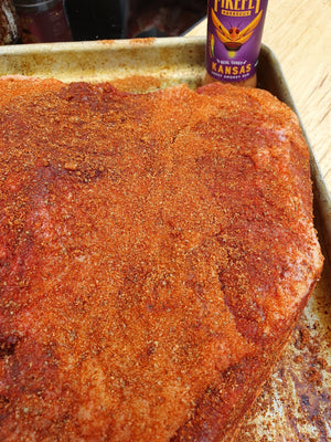 Raw brisket generously coated with Kansas BBQ Rub - Sweet & Smoky on a tray. Ideal for slow cooking or smoking meats.