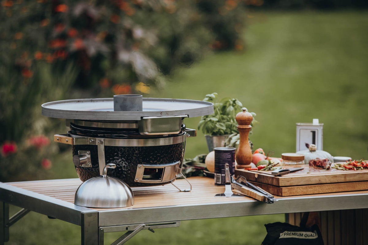 Close-up of Monolith BBQ with outdoor food preparation in garden