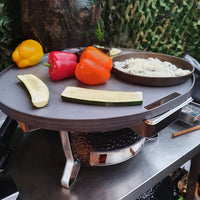 Vegetables and rice cooking on Monolith Fire Plate - Icon, showcasing multi-zone grilling on ceramic kamado grill in outdoor kitchen setup.