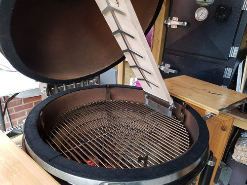 Beech Monolith Fish Plank attached to grill dome with stainless steel bracket, positioned above grill grate for indirect heat cooking.