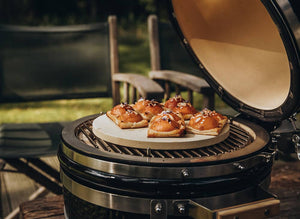 Pastries baking on a ceramic pizza stone inside the MONOLITH Icon Kamado Grill, demonstrating its versatility for outdoor baking.