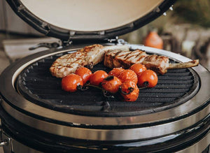 Grilled pork chops and cherry tomatoes on the MONOLITH Icon Kamado Grill, showcasing high-temperature searing capability.