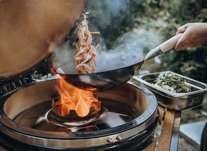 Stir-frying vegetables over open flame on Monolith Le Chef Pro Series 2.0 Kamado Grill, demonstrating wok compatibility and heat control.