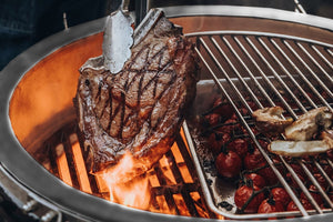 Close-up of steak and vegetables grilling over open flame on Monolith Le Chef Pro Series 2.0 Kamado Grill, showcasing high-heat performance.