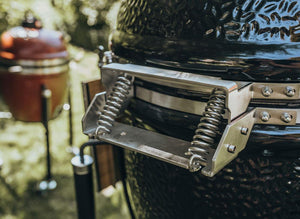 Close-up of Monolith Le Chef Pro Series 2.0 Kamado Grill hinge system, showing durable spring-loaded mechanism for smooth lid operation.