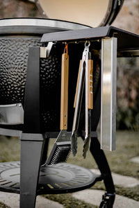 Outdoor grill with utensils hanging on side table