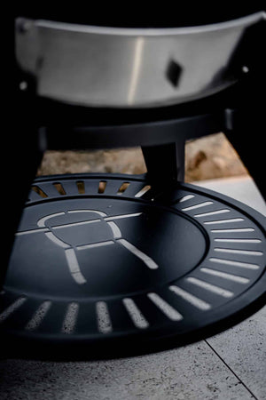 Black metal grill base with slotted design on textured surface