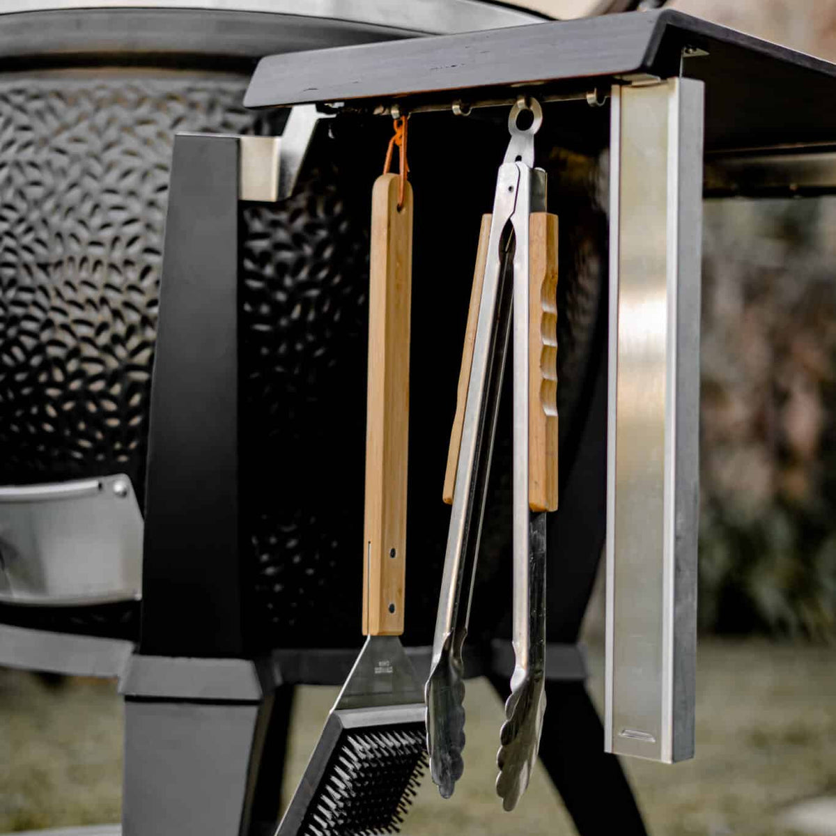 Monolith Kamado grill with grilling tools hanging on side for outdoor barbecue