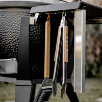 Monolith Kamado grill with grilling tools hanging on side for outdoor barbecue