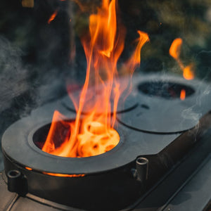 Top burner rings of Ozpig Big Pig stove with visible flames, showing its multi-functional outdoor cooking surface.