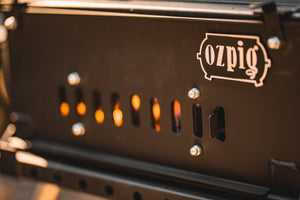Detailed view of Ozpig Big Pig stove vent with glowing fire inside, highlighting airflow control for outdoor grilling.