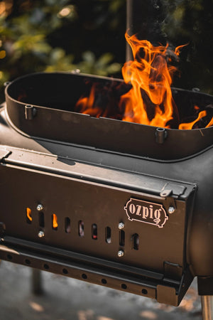 Close-up of Ozpig Big Pig stove front with flames and logo, emphasizing its robust design for outdoor cooking.