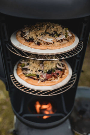 Ozpig Oven Smoker baking pizzas on multiple racks over wood fire, ideal for outdoor gourmet pizza preparation.