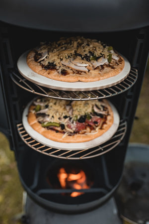 Two pizzas cooking on separate racks inside OzPig Oven Smoker. Perfect for outdoor baking with even heat distribution.