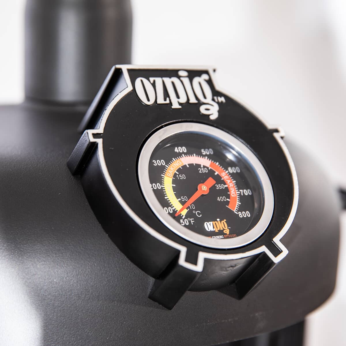 Close-up of OzPig Oven Smoker built-in thermometer showing temperature range from 100°C to 350°C. Ensures precise outdoor cooking control.