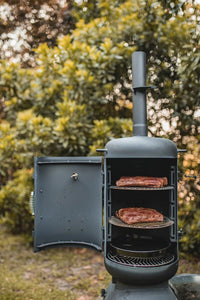 OzPig Oven Smoker in outdoor setting with ribs cooking on racks. Perfect for low and slow outdoor smoking and grilling.