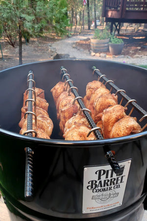 Pit Barrel PBX 22.5 Cooker in use with multiple chickens hanging inside, demonstrating vertical cooking efficiency.