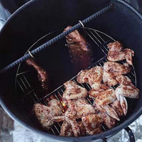 Pit Barrel Hinged Grate loaded with seasoned chicken wings and hanging ribs, demonstrating dual cooking zones in a vertical smoker.