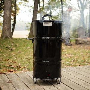 Pit Barrel Junior Cooker in use outdoors on a wooden deck, perfect for backyard smoking and grilling with compact portability.