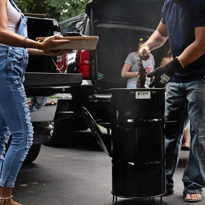 Tailgating scene with Pit Barrel Junior in use, highlighting its portability and ease of use for outdoor gatherings and events.