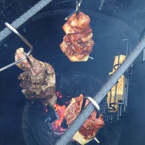 Inside view of Pit Barrel Junior with meat and corn hanging over coals, showing vertical cooking style for even heat distribution.