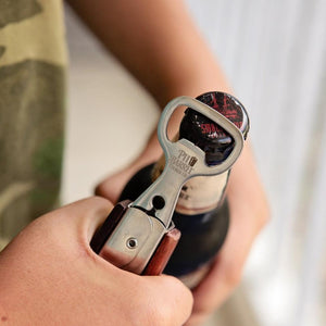 Pit Barrel Ultimate Tongs used as a bottle opener, emphasizing its multifunctional design ideal for BBQ and beverage enjoyment.