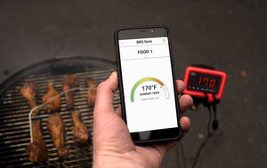 Hand holding smartphone displaying BBQ Guru UltraQ BBQ Controller - Monolith Guru Edition app with 170°F food temperature reading.